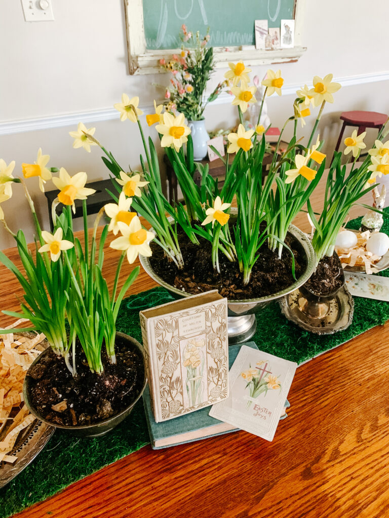 Dining room Easter tablescape with daffodils, vintage books and postcards
