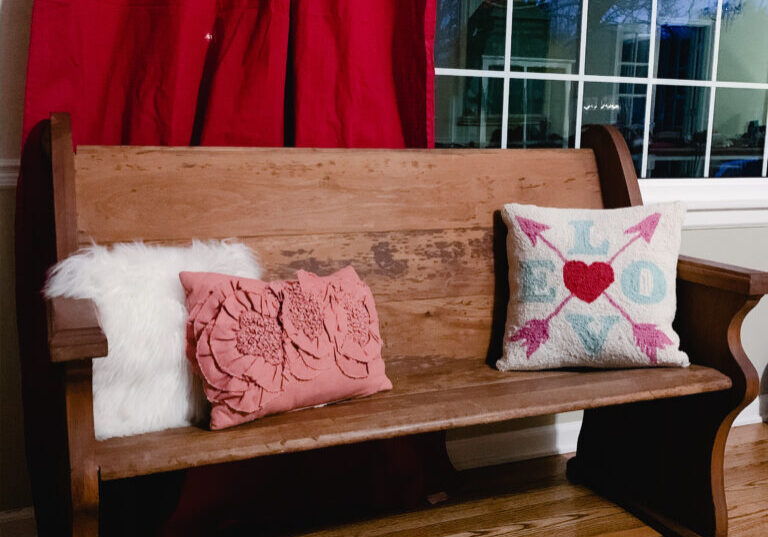 Church pew with pink pillow and red drapes for Valentine's Day